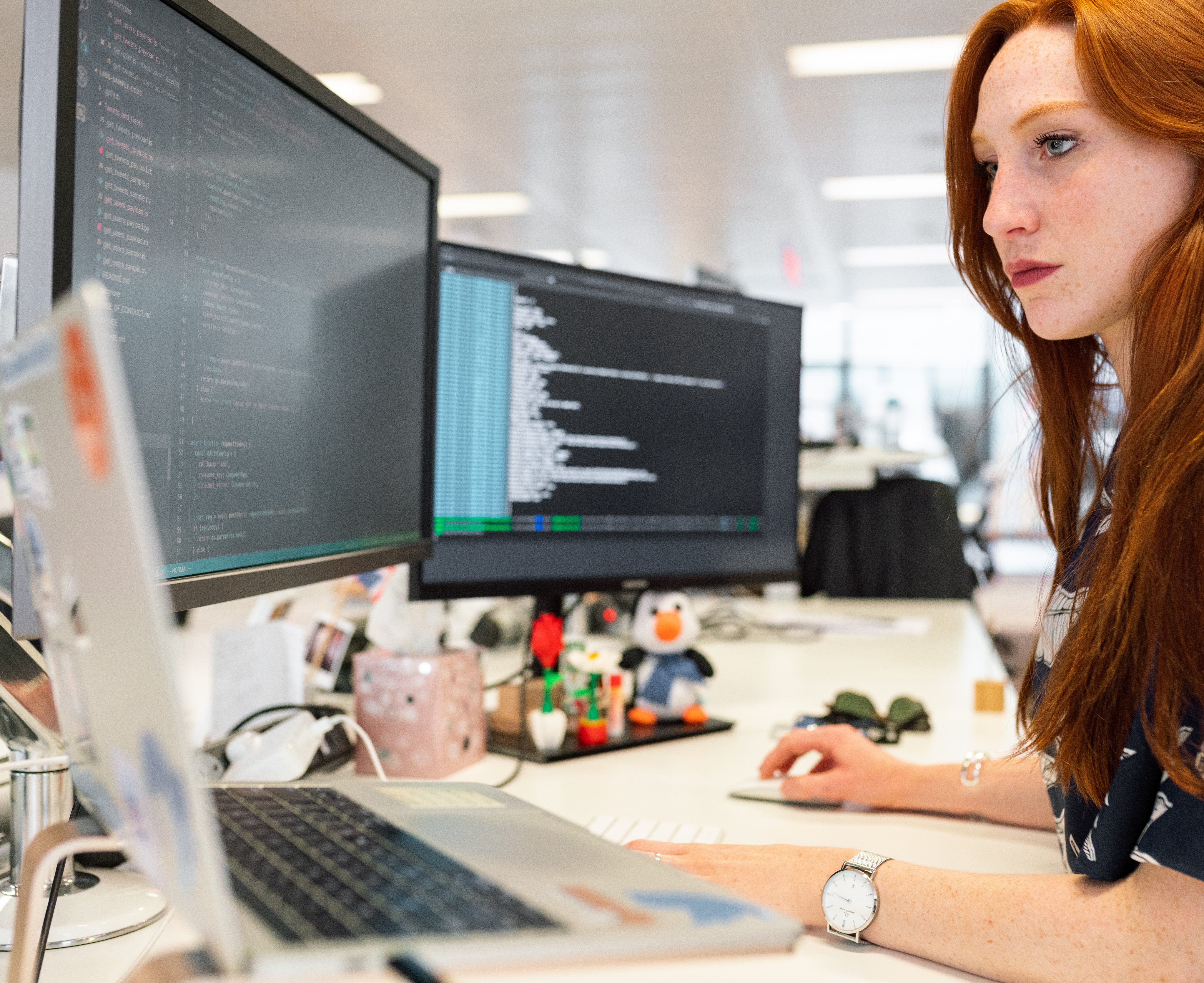 woman coding on monitors