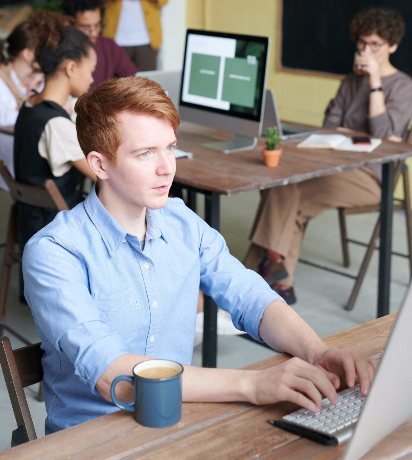 Redheaded man working on laptop with coffee