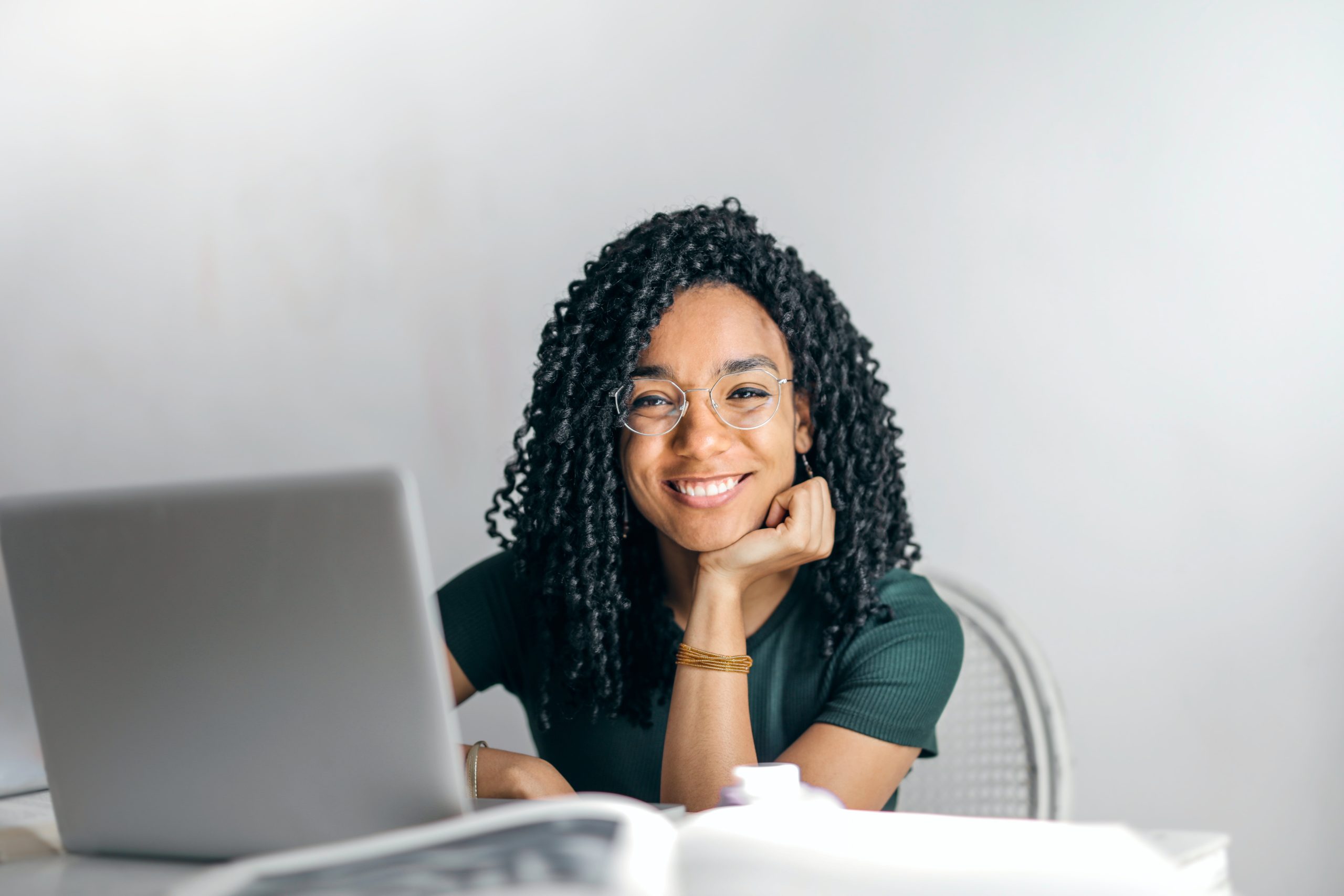 woman smiling at camera while using laptop