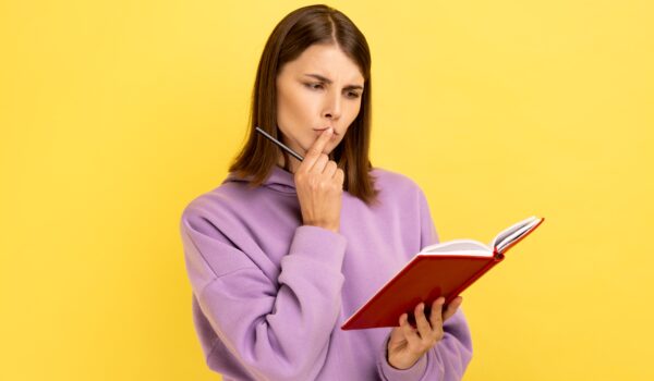 woman holding a notebook and pondering questions