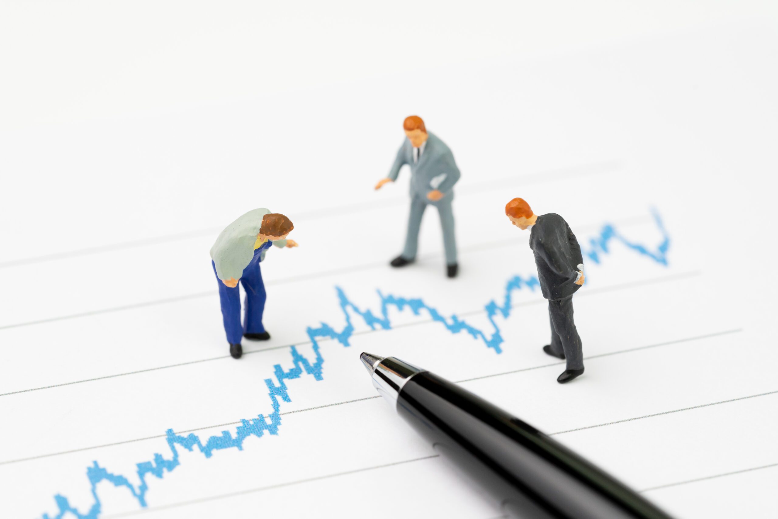 Miniature businesspeople examine a line chart.