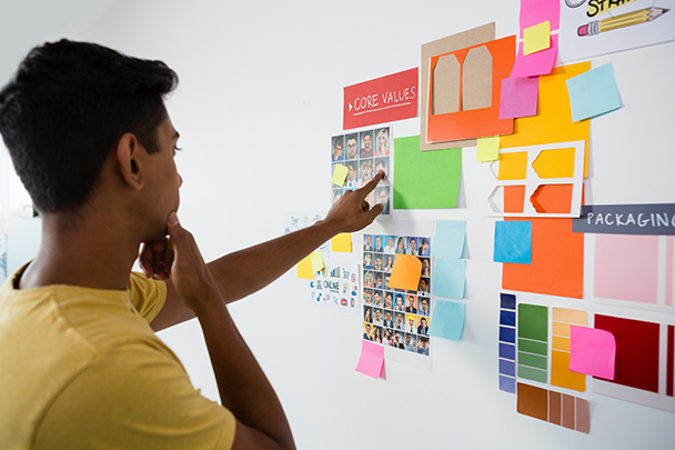 Young man looking at sticky notes, planning digital PR campaign