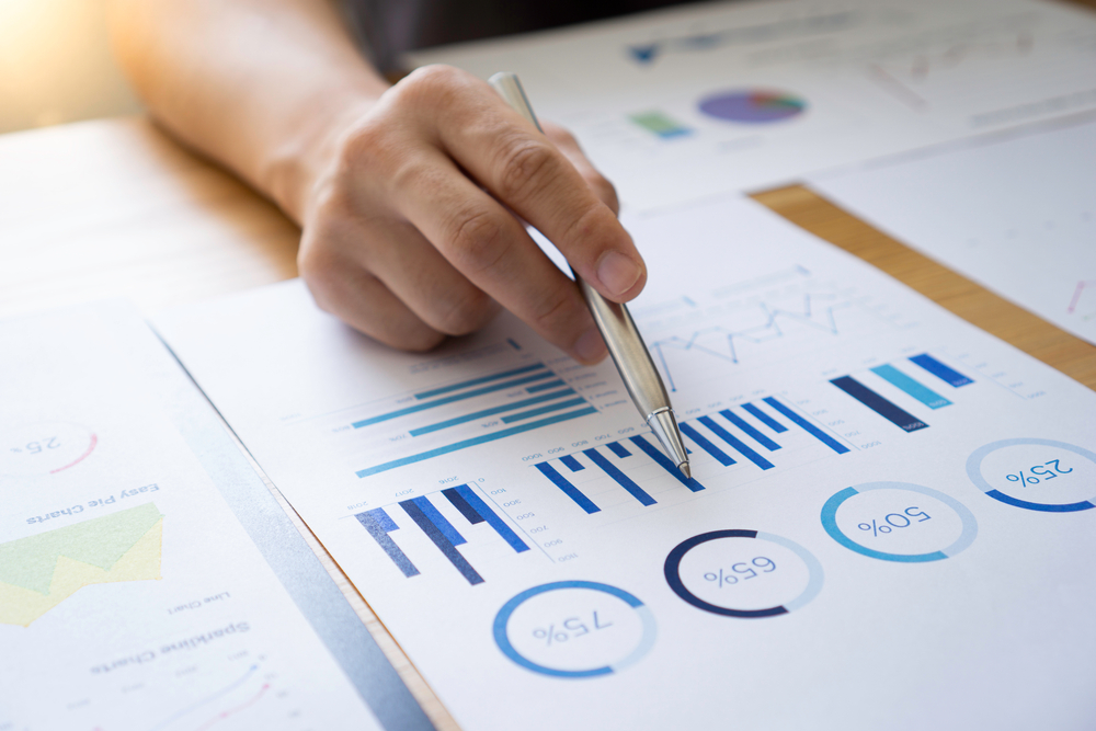 hand holding pen pointing at graph data on a piece of paper